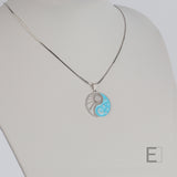 Halskette Yin Yang Cosmique Leuchtend blaue Lackierung, Schlangenkette, Atelier-Émile in Rhodium, Beschichtung  hergestellt in der Schweiz, Vorderansicht auf weißem Hintergrund