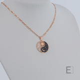 Halskette Yin Yang Cosmique Laque Noir Atelier-Émile, 18 Karat Roségold plattiert mit 24 Karat Finish, 10 bis 15 Mikron dickes Plattierungsmaterial, hergestellt in der Schweiz, montiert auf einer Figaro-Kette, Vorderansicht auf weißem Hintergrund