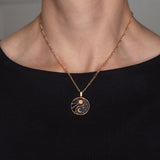 Halskette Yin Yang Cosmique Laque Noir Atelier-Émile, 18 Karat Roségold plattiert mit 24 Karat Finish, 10 bis 15 Mikron dickes Plattierungsmaterial, hergestellt in der Schweiz, montiert auf einer Figaro-Kette, getragen, Ansicht von vorne auf schwarzem Hintergrund