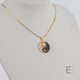 Halskette Yin Yang Cosmique Laque Noir Atelier-Émile aus 18 Karat Gelbgold mit 24 Karat-Finish, 10 bis 15 Mikron dicke Beschichtung, hergestellt in der Schweiz, montiert auf einer Schlangenkette, Vorderansicht auf weißem Hintergrund
