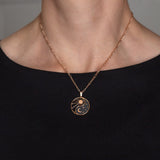 Halskette Yin Yang Cosmique Laque Noir Atelier-Émile, 18 Karat Roségold plattiert mit 24 Karat Finish, 10 bis 15 Mikron dickes Plattierungsmaterial, hergestellt in der Schweiz, montiert auf einer Figaro-Kette, getragen, Ansicht von vorne auf schwarzem Hintergrund